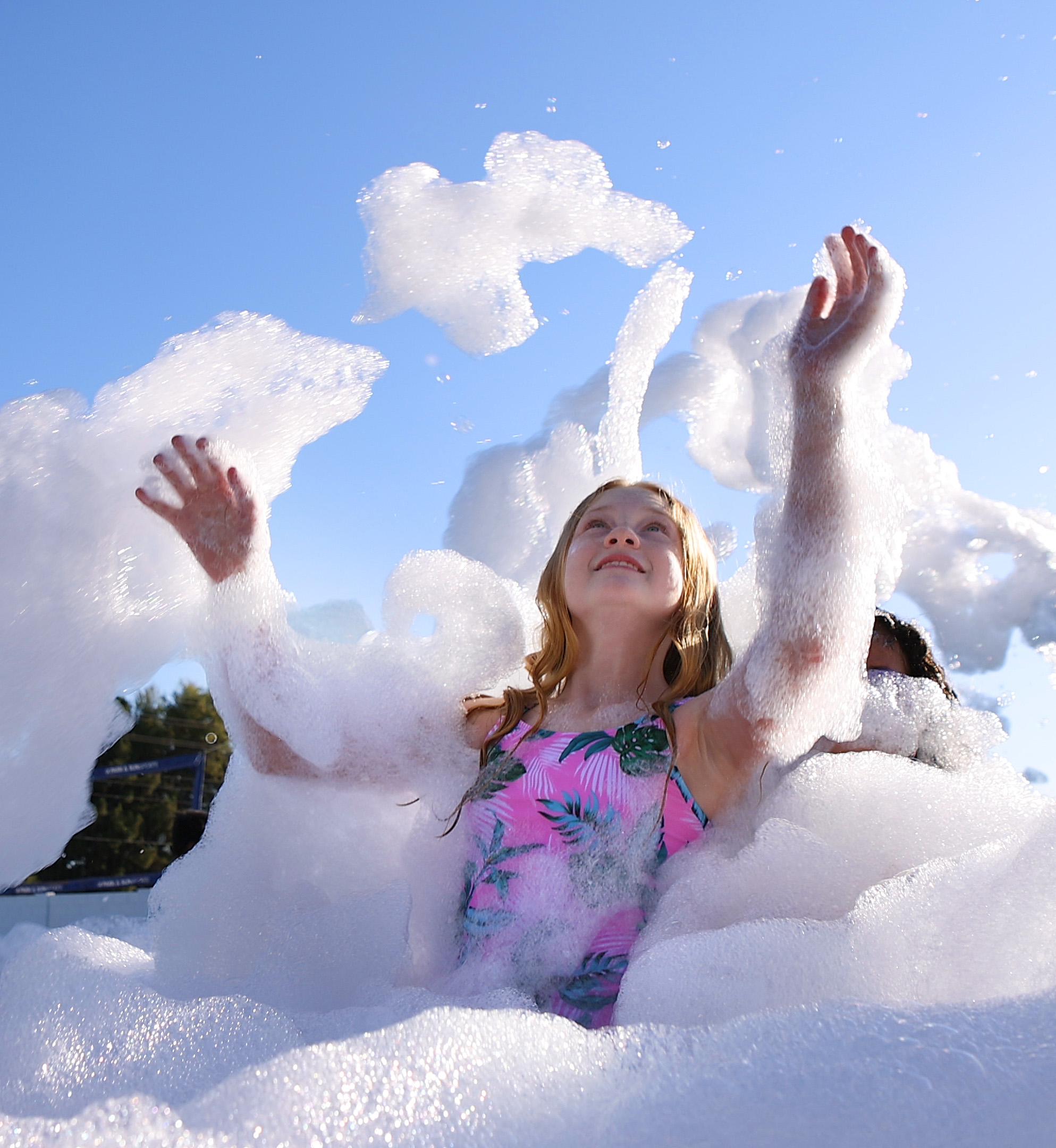 A child tossing bright white foam into a blue sky