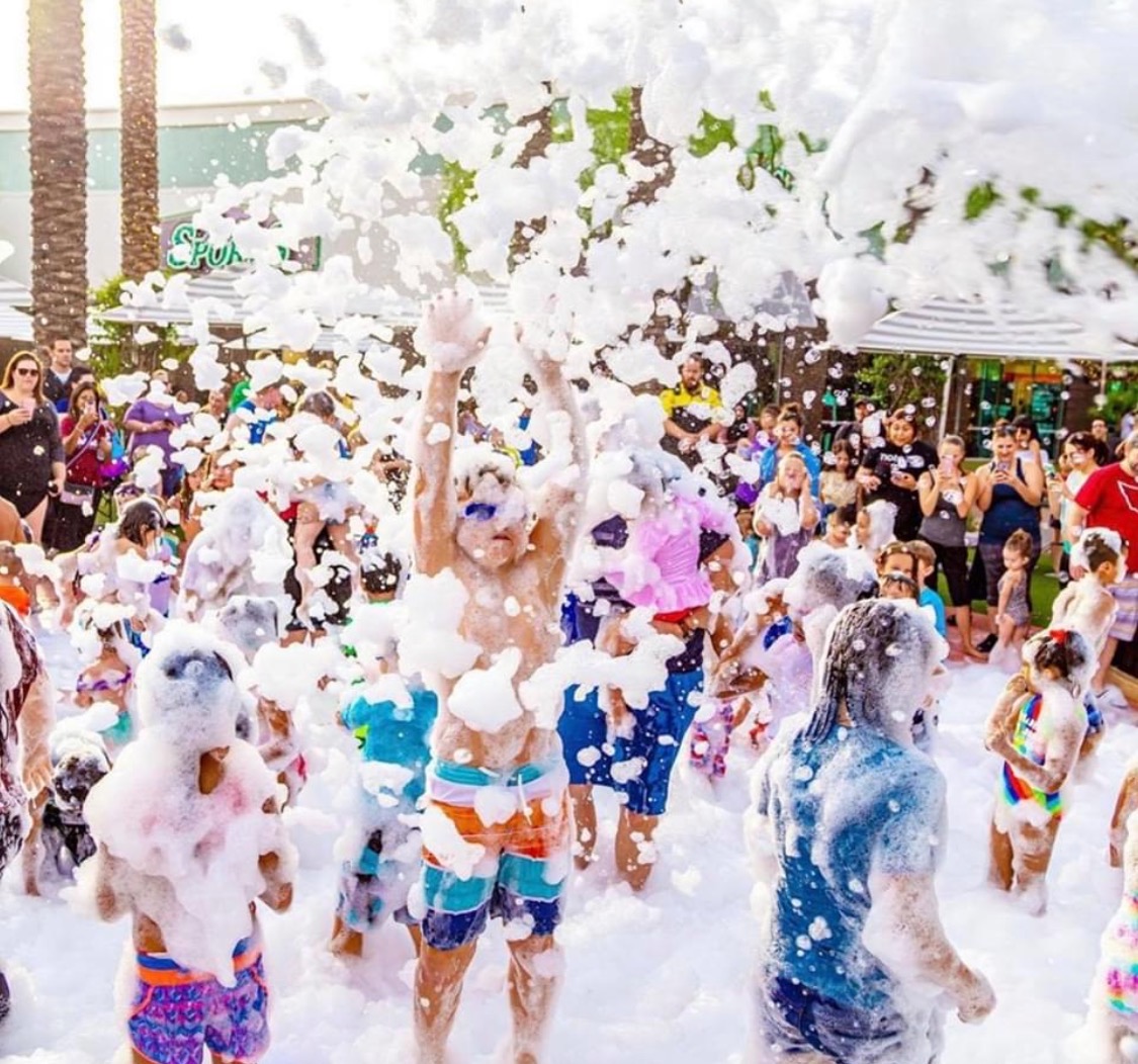 A large crowd celebrating in a cloud of foam