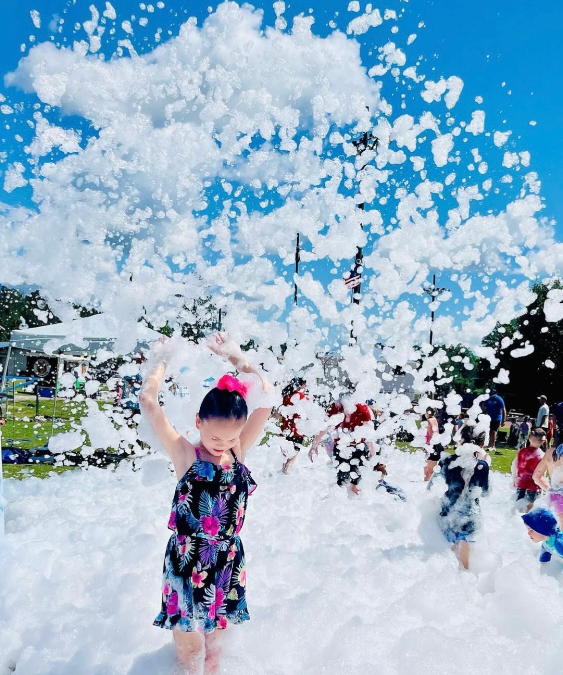A child lifting foam overhead at a sunny outdoor event