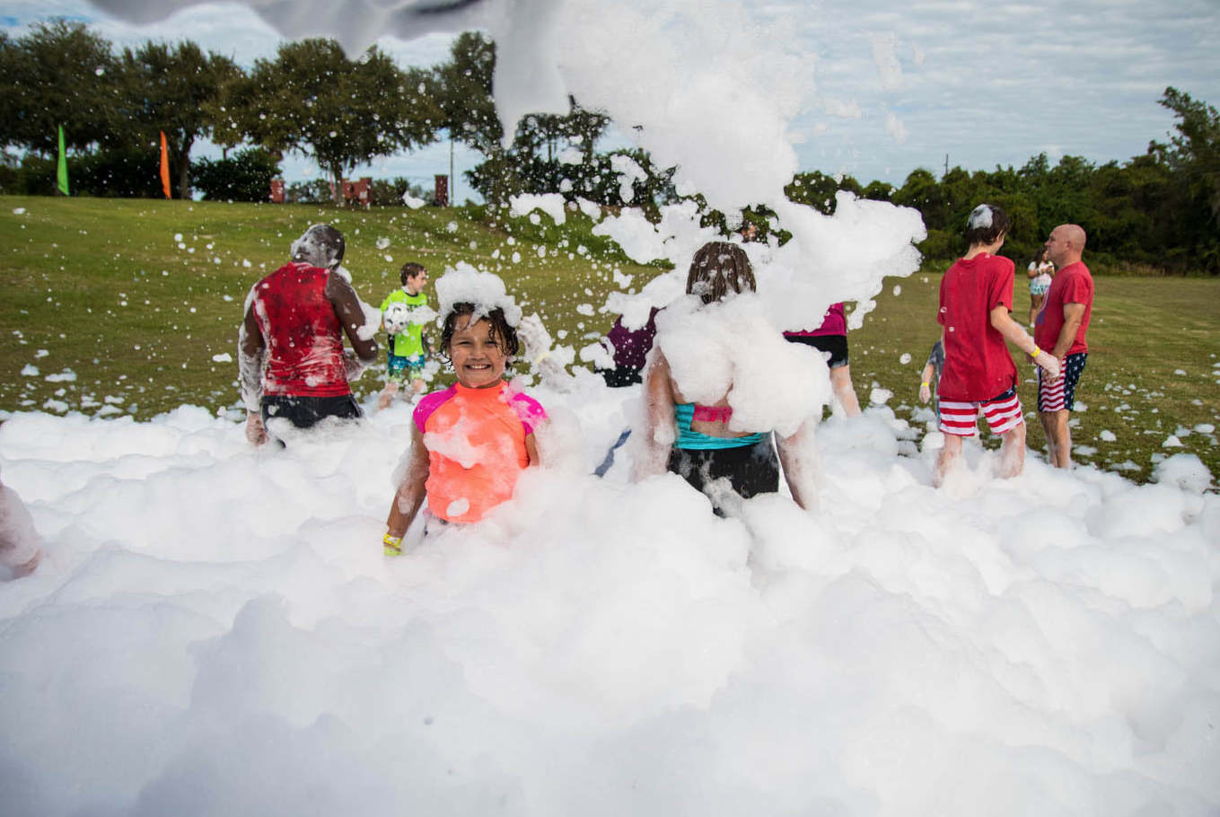 Families playing in a wide field filled with foam