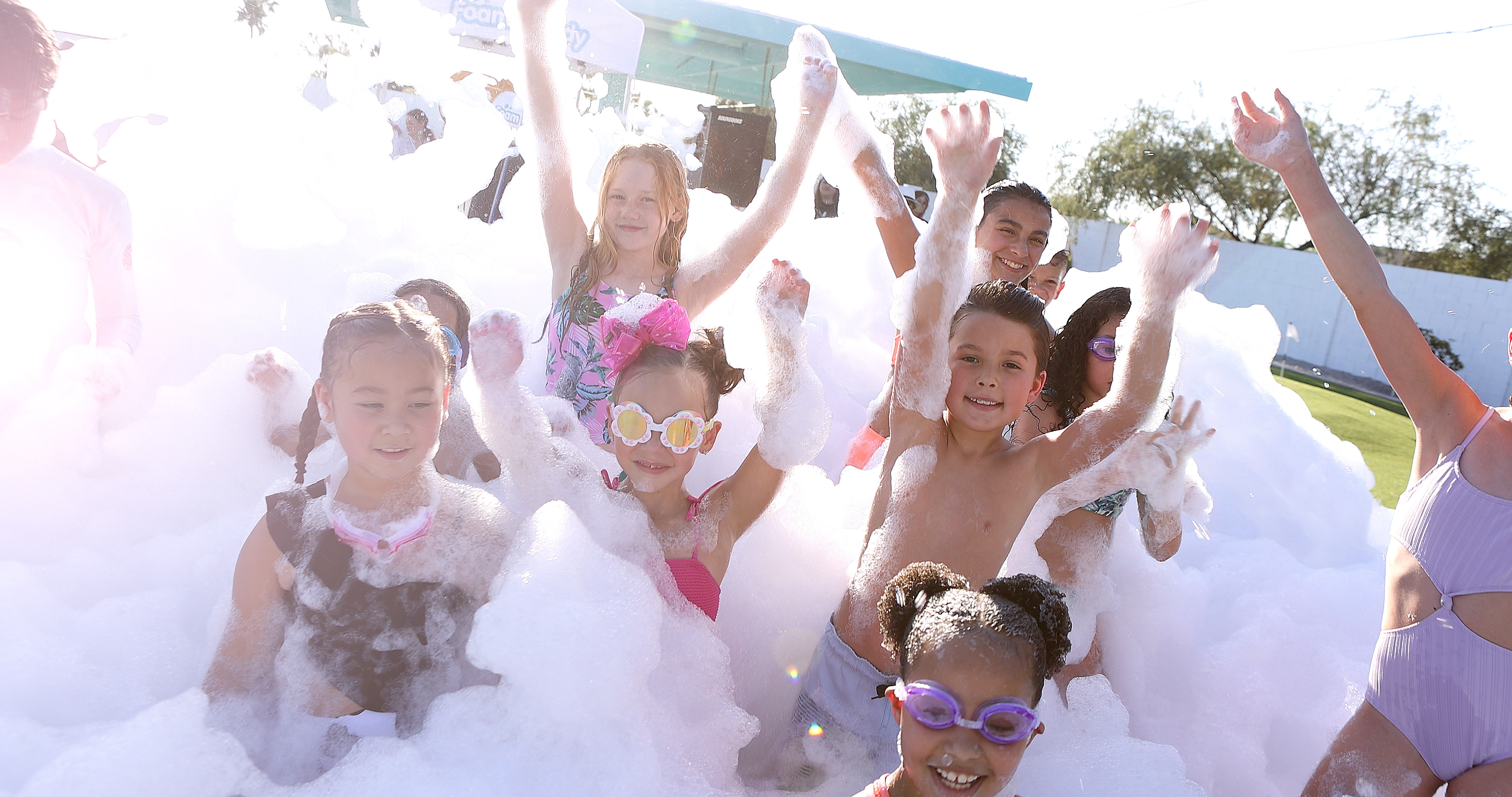 A group of children cheering in a mountain of foam