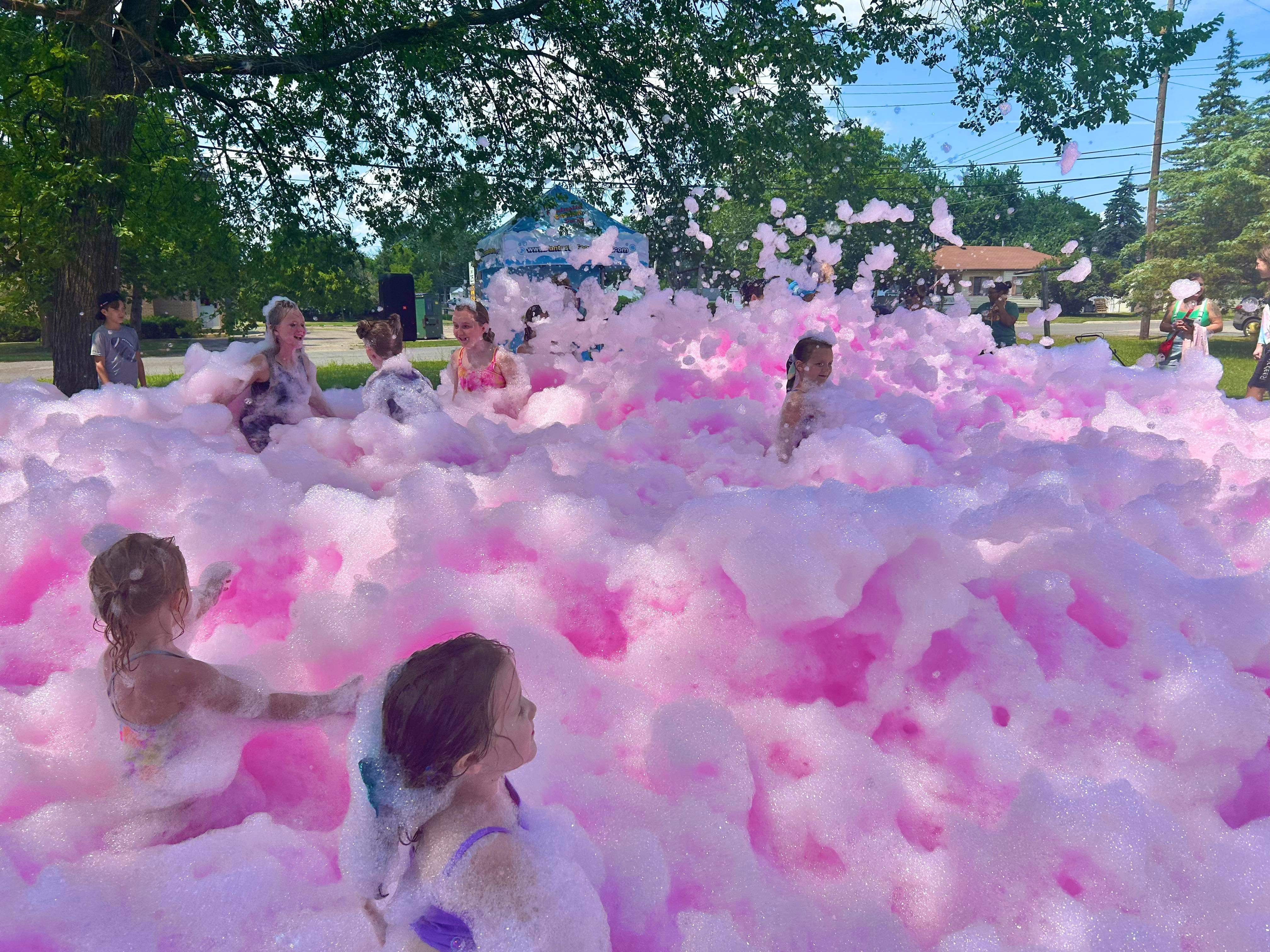 Children playing in colorful pink foam outdoors