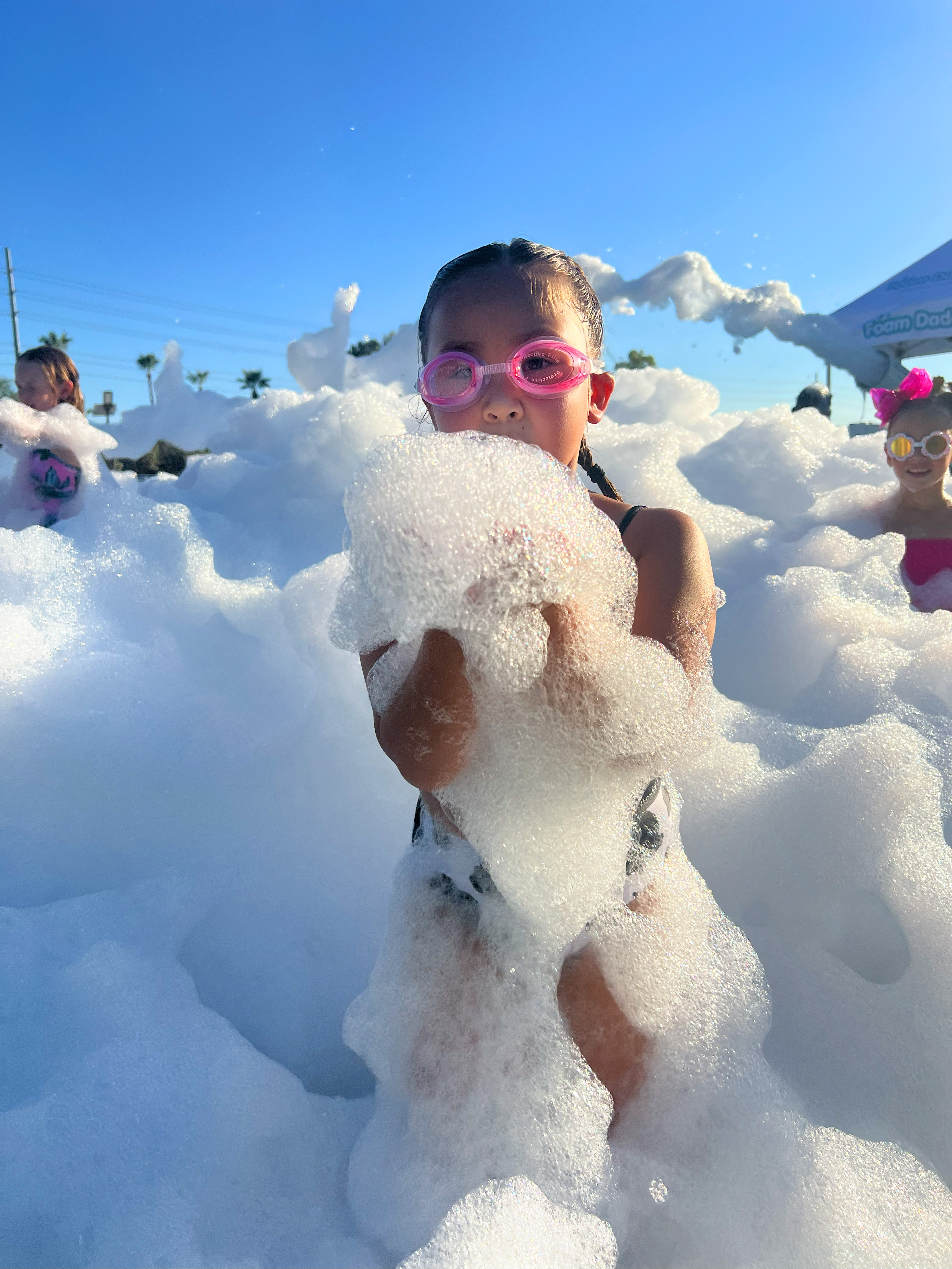 A child in pink goggles holding a bundle of foam